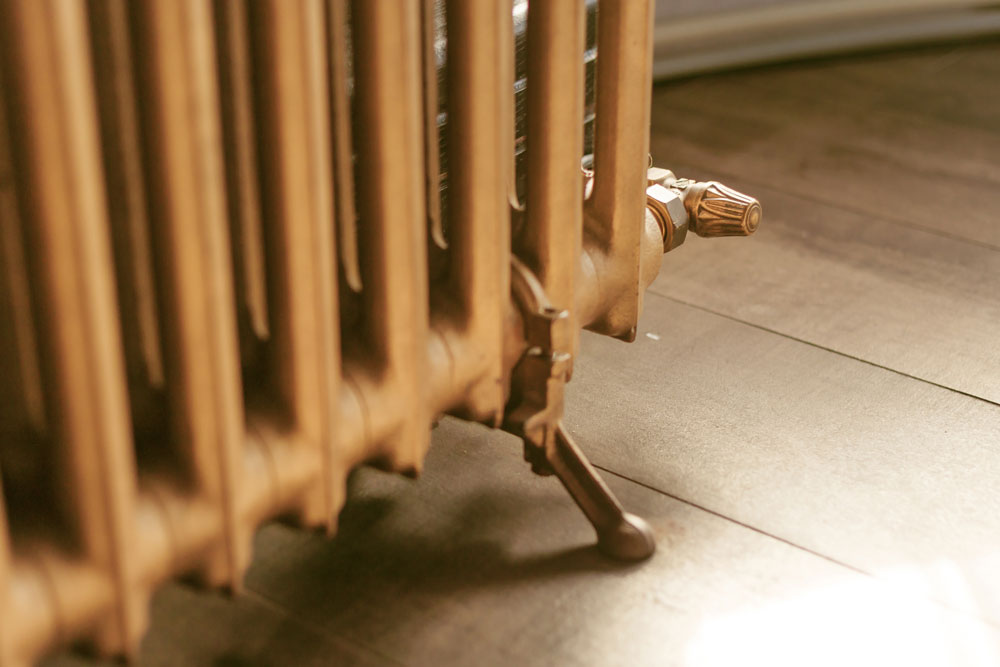 Image of a person draining a cast iron radiator